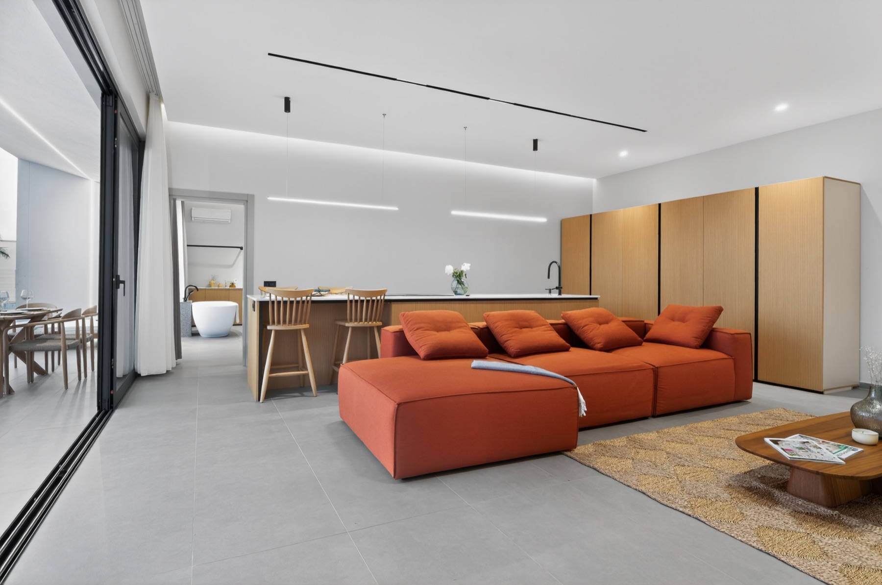 Geniş salon; turuncu kanepe ve terasa açılan cephe.