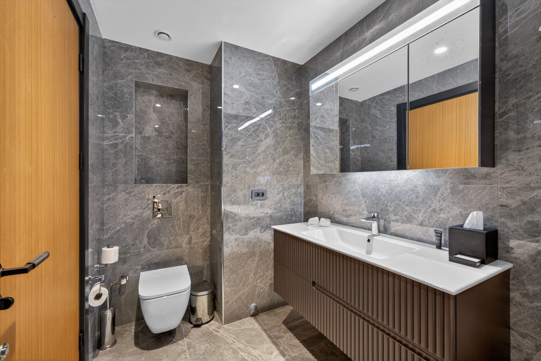 Banyo; mermer duvar, çift lavabo ve camlı duş.